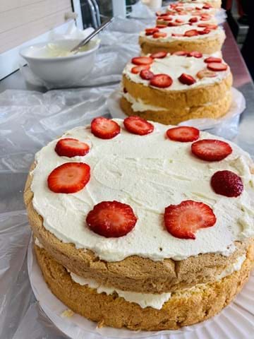 A line of sponge cakes with cream and topped with strawberries